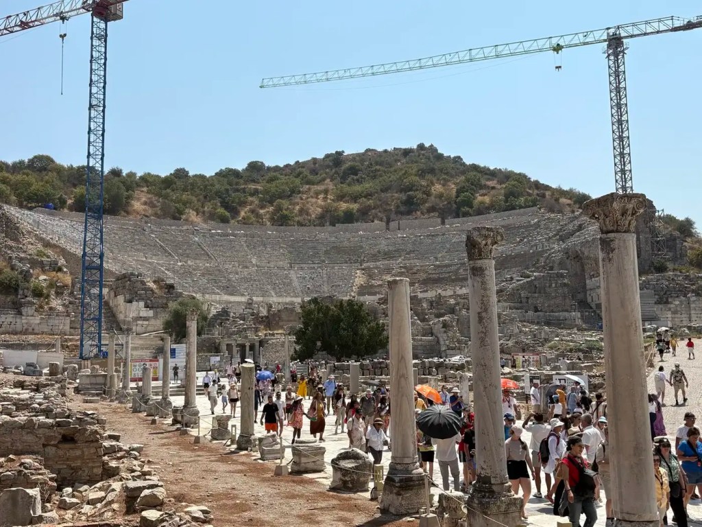 The Great Theatre of Ephesus with ancient columns, visitors, and restoration work visible