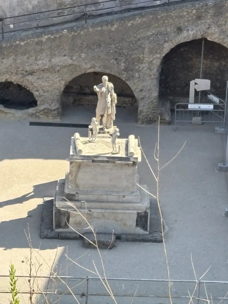 Ancient marble statue displayed on a pedestal among stone arches at Herculaneum