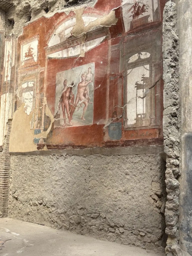 Preserved red Roman wall frescoes with painted figures and architectural scenes at Herculaneum