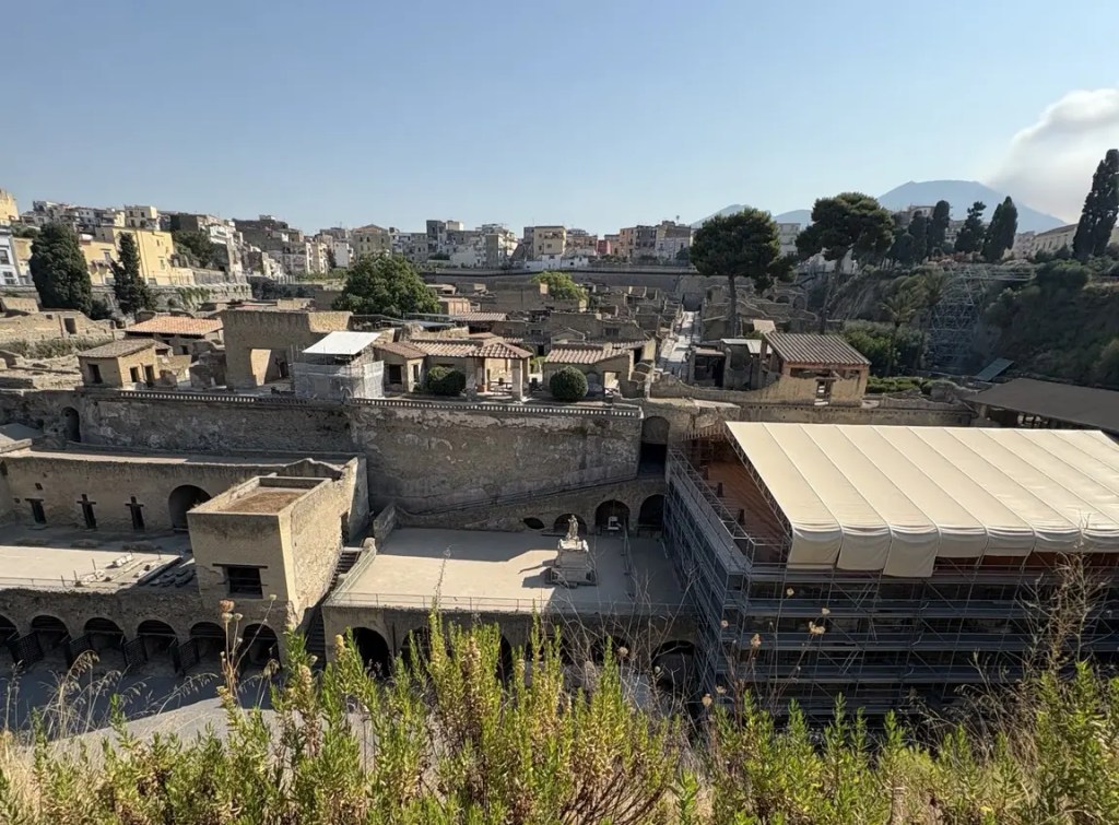 Wide view across the ancient buildings of Herculaneum with Mount Vesuvius rising in the distance