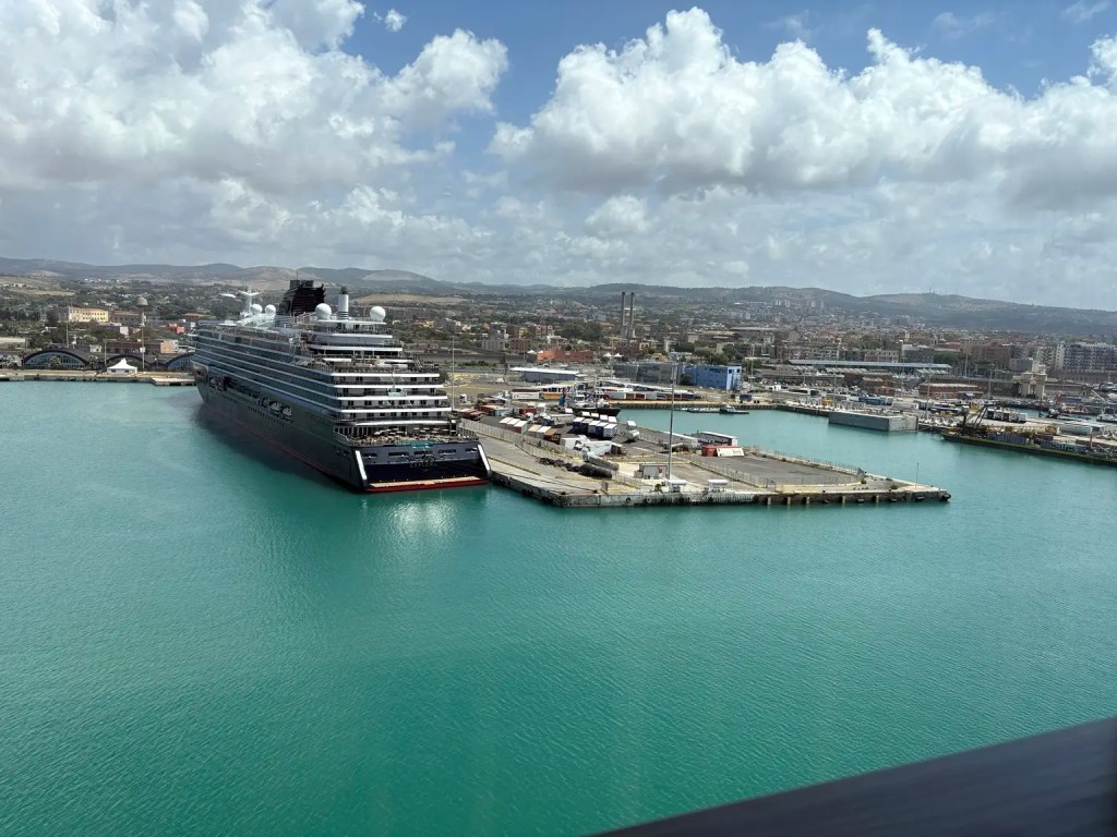 Cruise ship docked at a Mediterranean port across turquoise water