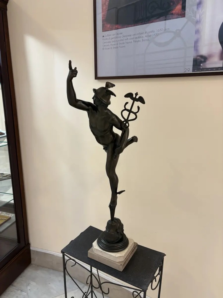 Dark bronze sculpture of Mercury holding a caduceus inside a cameo jewelry shop near Naples