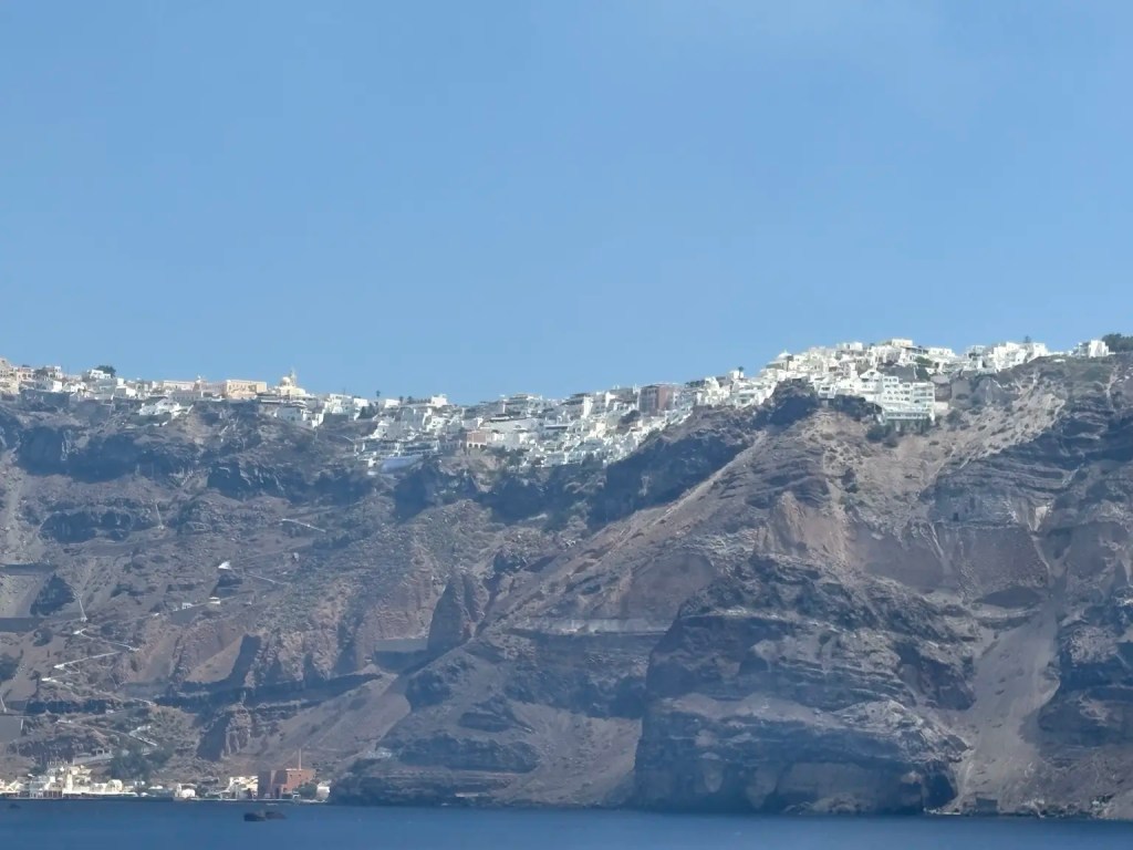 Whitewashed villages lining the top of Santorini’s steep caldera cliffs