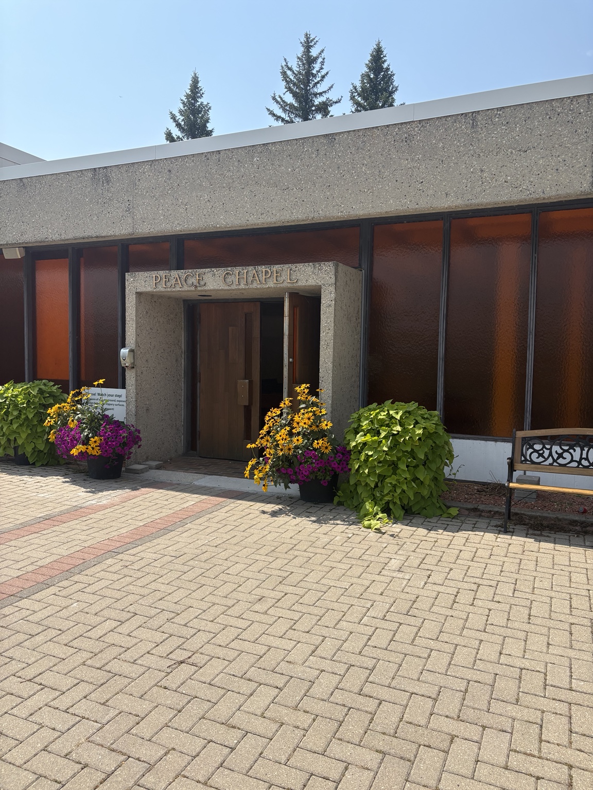 The Peace Chapel entrance framed by flower planters and amber-colored windows.