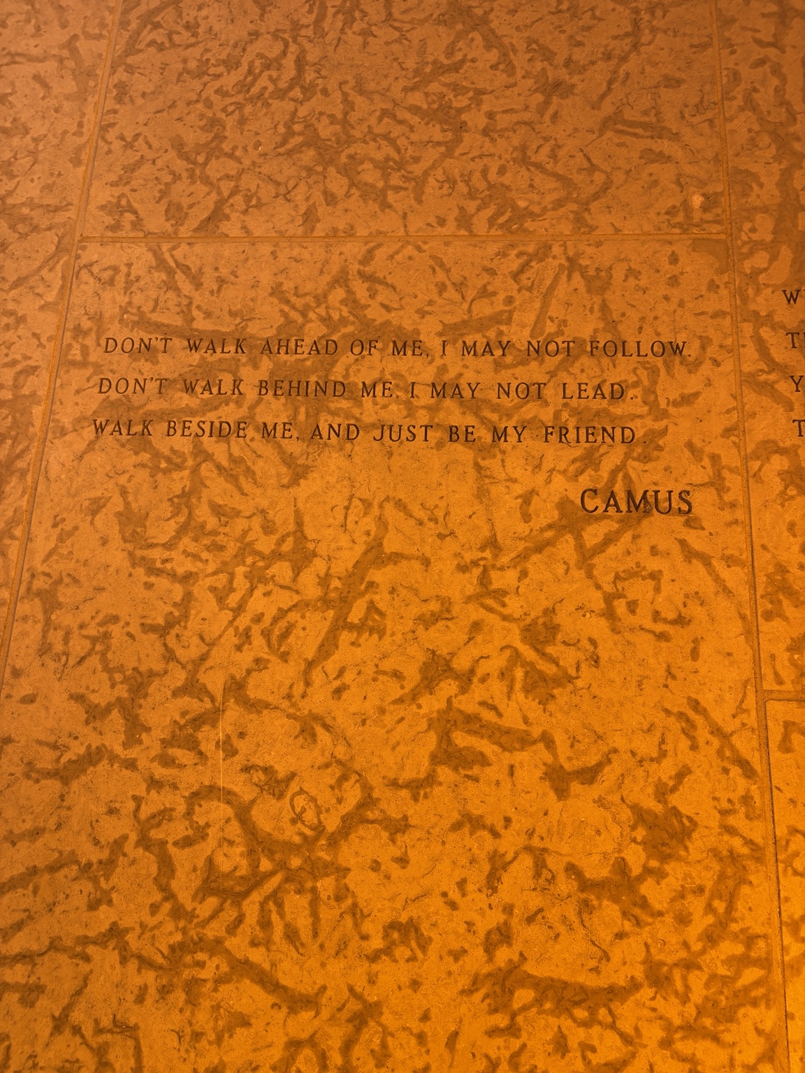 An inscription about friendship on a warmly lit stone wall inside the Peace Chapel.