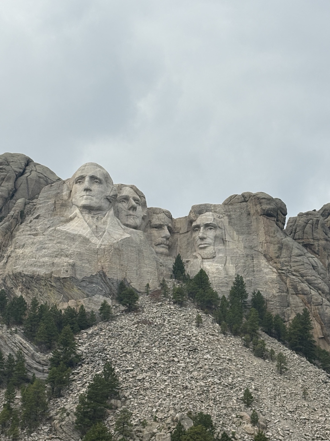 The four presidential faces carved into Mount Rushmore above pine trees and a rocky slope.