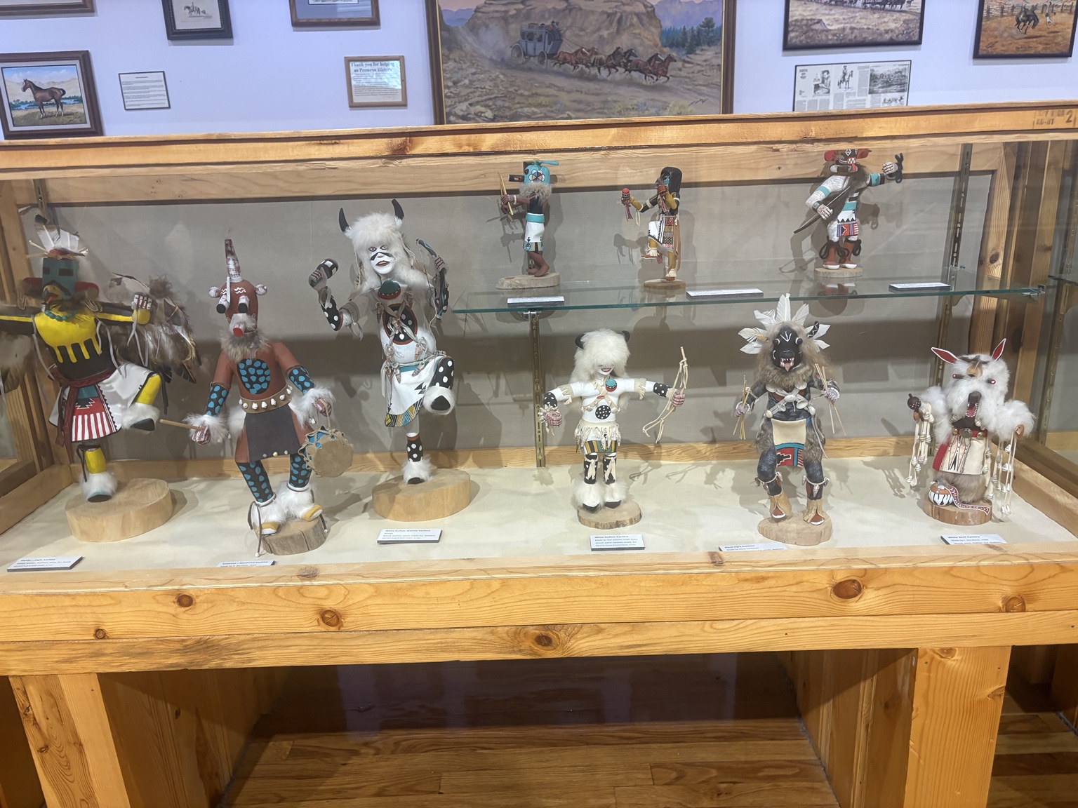 Detailed painted figures displayed in a glass museum case at Crazy Horse Memorial.