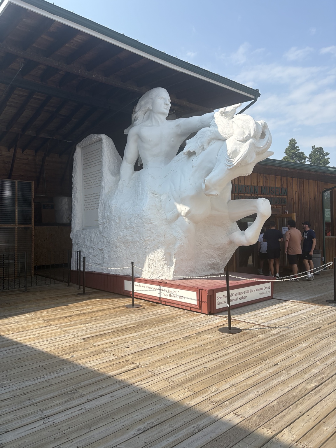 A white scale model of Crazy Horse on horseback with an outstretched arm.