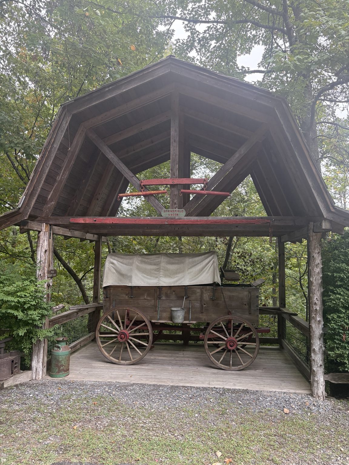 Historic covered wagon displayed beneath a wooden shelter.