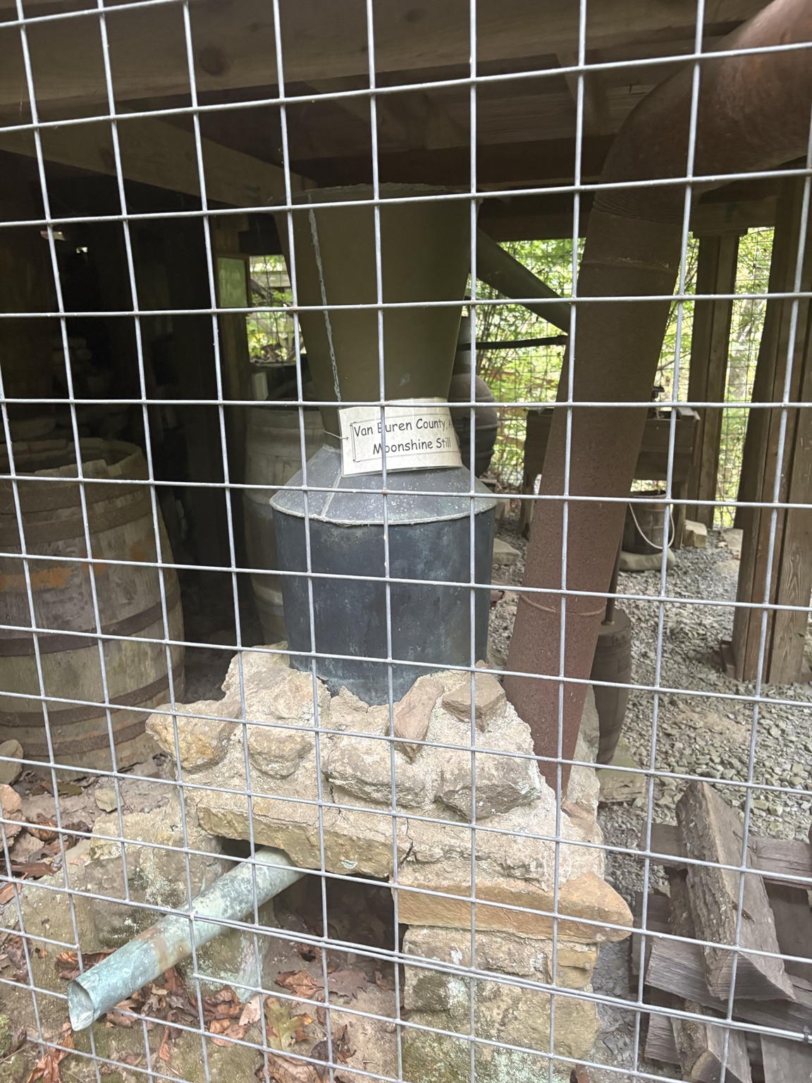 Van Buren County moonshine still displayed behind a wire fence.